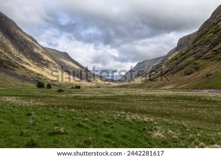 The stark beauty of the Highlands is evident as craggy slopes flank a wide valley under a brooding sky. Isle of Skye, Scotland