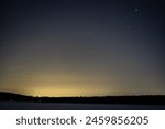 Starry Night Over Frozen Lake: A serene night sky filled with stars above a frozen lake lined with snow-covered rocks.