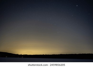 Starry Night Over Frozen Lake: A serene night sky filled with stars above a frozen lake lined with snow-covered rocks. - Powered by Shutterstock