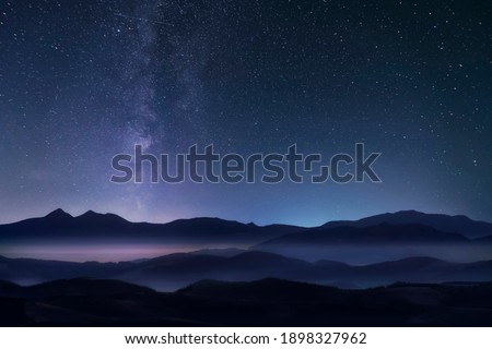 Starry night sky with milky way over the mountains. Soft focus.