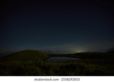 Starry night sky over a serene mountain lake reflecting distant lights in a tranquil landscape - Powered by Shutterstock