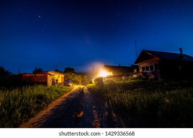 Starry night sky over village house in summer. Wooden house with one bulb light over entrance. Russia. - Powered by Shutterstock