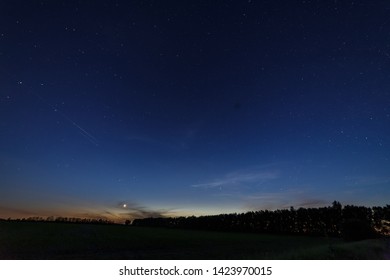 Starry Sky After Sunset Over The Field And Trees. Planet Venus Is Above The Horizon.