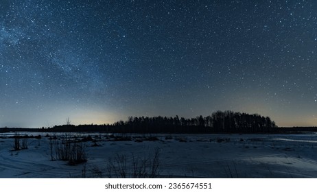 Starry sky by a frozen lake and a forested island in winter in Finland - Powered by Shutterstock