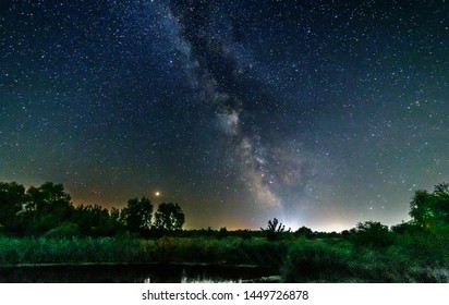 Starry Sky And The Milky Way Over Water And Trees.