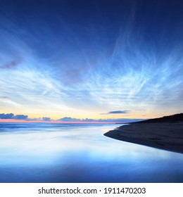 Starry sky with noctilucent clouds above the Baltic sea shore at summer solstice night. Golden flowing sunlight. Long exposure. Fantastic cloudscape. Natural pattern. Abstract art. Latvia - Powered by Shutterstock