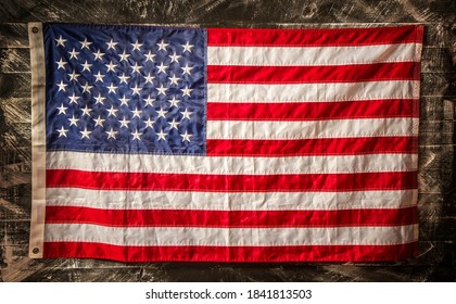 the stars and stripes of the United States of America hanging on a rough dark wooden surface