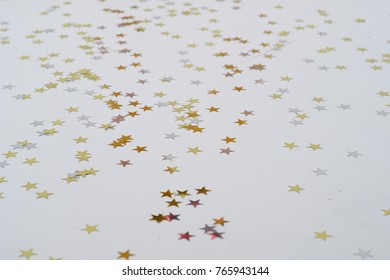 Star-shaped Gold And Silver Color Confetti On A White Floor