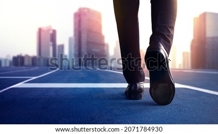 Start, Competition Concept. Low Section of Businessman Steps into Start Line on Running Track and Moving Forward to New Challenge. Blurred City Building as background