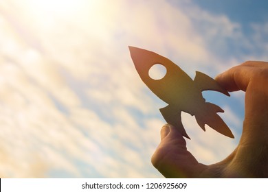 Start up concept. Rocket in the hand of a businessman against the sky in the rays of the sun. Business idea, creative. success and achievement, career growth.