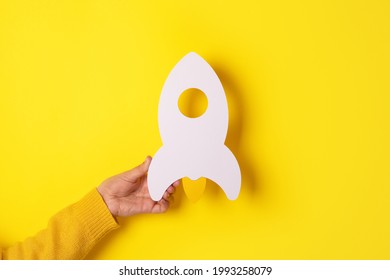Start up concept with rocket in hand over yellow background,investment, success ideas