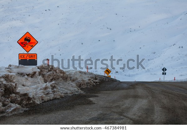 The start of the\
descent down from the top of the Crown Ranges, an orange warning\
sign is in use during winter to warn of ice and grit on the road,\
South Island, New Zealand.