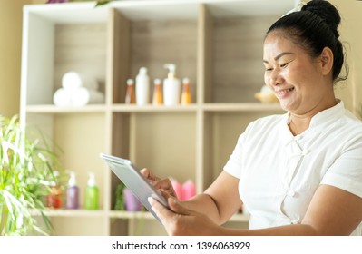 Start Up Of Enterprise. Portrait Of Asian Woman Massage Spa Owner Using Tablet Responding On Business Email, Social Network With Customer Or Booking Queue For Service Massage Spa At Spa Center Hotel.