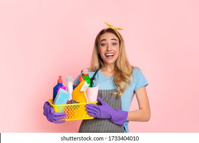 Start Of House Cleaning. Happy Housewife With Basket With Cleaning Supplies Isolated On Pink Background, Studio Shot