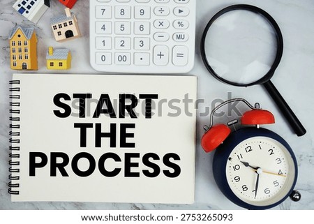 Start The Process text written on notepad with house model, calculator, magnifying glass and alarm clock on marble background