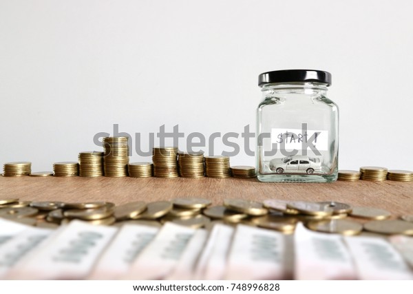 Start
saving money concept, empty glass jar and rolls ladder of gold
coins on wood table in white background          
