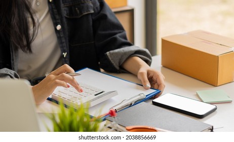 Start small business, independent SME entrepreneur, Asian woman working at home portrait with Boxes and laptops to receive orders from customers online, marketing, packaging, shipping, SME, ecommerce 