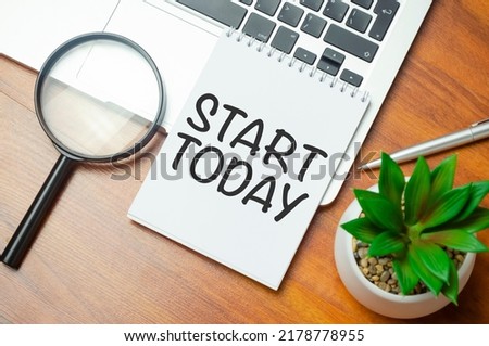 start today text on notepad and laptop on wooden background