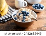 Start your day right with nutritious oatmeal, blueberries, and banana, for a healthy and delightful morning. Wooden table background, closeup view