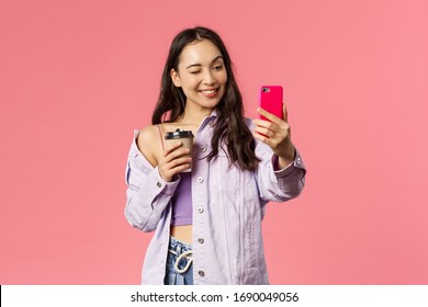 Start Your Day Right. Portrait Of Good-looking Enthusiastic Young Asian Girl In Stylish Outfit, Taking Selfie With Take-away Coffee, Recommend Followers Great Cafe To Grab Drink, Pink Background