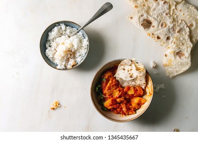 Started eaten Vegan vegetarian curry with ripe yellow jackfruit served in ceramic bowl with rice, coriander and homemade flatbread flapjack over white marble background. Flat lay, space