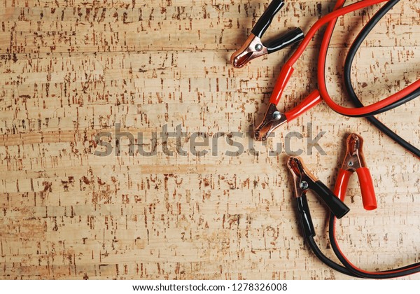 starter car ignition cable, dead\
battery, wood background, power cables for emergency\
charging