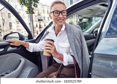 Starting Day With Coffee. Beautiful Middle Aged Business Woman Arrived At Work, She Is Getting Out Of Her Modern Car And Smiling