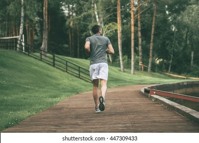 Starting Day From Morning Jog. Full Length Rear View Of Young Man In Sports Clothing Jogging In Park  