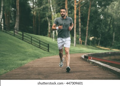 Starting Day From Morning Jog. Full Length Of Handsome Young Man In Sports Clothing Jogging In Park  