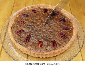 Starting to slice a freshly baked pecan pie on a wooden table