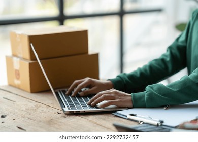 Starting a small business, SME, business owners use laptops to type communications, take orders, and check online purchase orders to prepare packages.