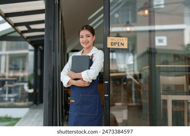 Starting a successful small business Small business owner SME Beauty Girl stands holding an open sign in front of a coffee shop. Coffee shop owner, female Asian barista, SME entrepreneur. - Powered by Shutterstock