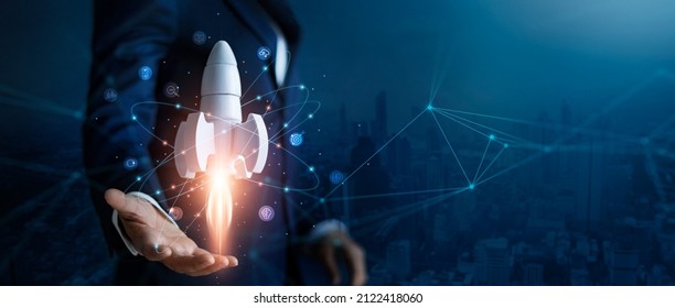 Startup business concept, Businessman control white rocket is launching and soar flying out from hand to sky for growth business,  Fast business success. Network connection on city background. 