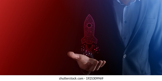 Startup business concept, Businessman holding tablet and icon rocket is launching and soar flying out from screen with network connection on dark background