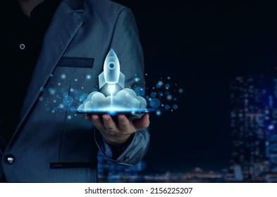 Startup business concept. Businessman holding a tablet, rocket launching and soar flying out from screen, starting a business, growing business, modern technology, hologram, network connection.