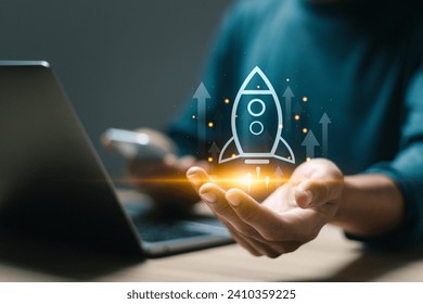 Startup business concept, Businessman use laptop with virtual screen of rocket icon and up arrow for fast start up business. Strategic planning and business success.