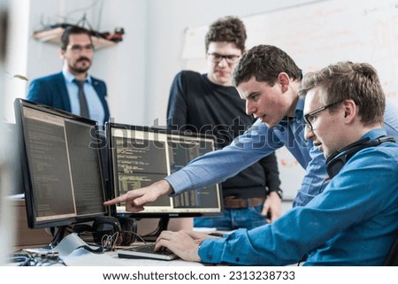 Startup business and entrepreneurship problem solving. Young AI programmers and IT software developers team brainstorming and programming on desktop computer in startup company share office space.
