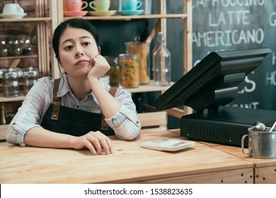 startup business owner woman waiting for customers leaning on bar counter with hands on chin. upset asian japanese lady waitress feels bored and depressed with bad poor finance in cafe restaurant.