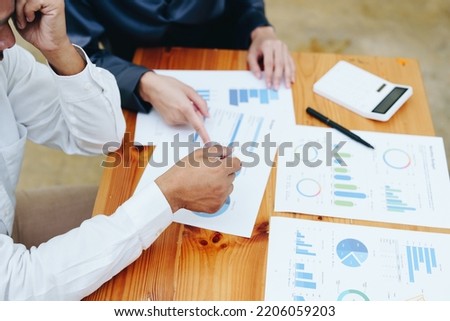 startup business, a portrait of two entrepreneurs using computers, calculators and financial budget documents to plan marketing efforts to increase profits.