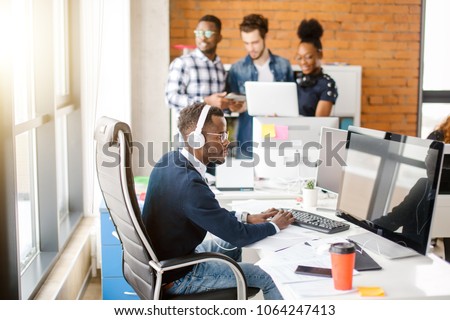 startup business worker is typing important document with wearing headphones because of the noisy room