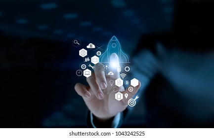 Startup concept. Businessman touching icon transparent rocket is launching and flying out with icon network connection on modern virtual interface. - Shutterstock ID 1043242525