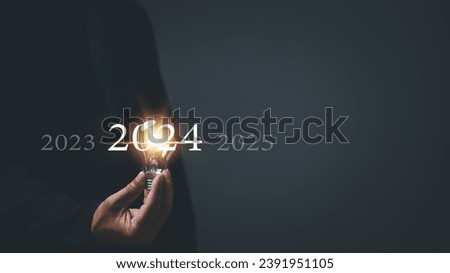 Startup concept. Man holding a light bulb. With a clear vision and strategic plan, a determined businessman navigates the trends of 2024, paving the way for a prosperous future.
