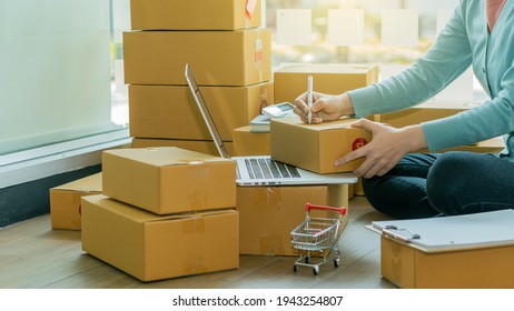 Startup Entrepreneurship Small Business SME Freelance Young lady working at home with boxes on the floor and laptop online Marketing Packaging SME Shipping Ecommerce Concepts