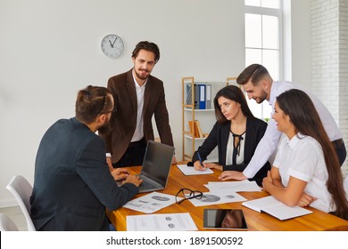 Startup Group Meeting Around Office Desk In Creative Workspace. Start-up Leader Listening To Teammates' Suggestions, Talking, Discussing Budget Issues And Work Needs. Sales Team Analyzing Results