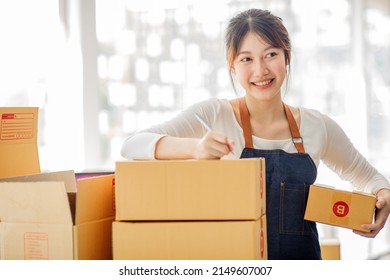 Startup Happy Asian Woman Business Owner Works With A Box At Home, Prepare Parcel Delivery SME Supply Chain, Procurement, Package Box To Deliver To Customers, Online SME Business Entrepreneurs Ideas,