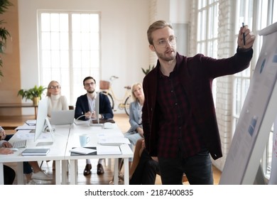 Startup Leader Presenting Charts To His Team In Meeting Room. Manager Explaining Sales Reports On Flipchart To Employees. Corporate Trainer Giving Marketing Workshop To Staff. Presentation Concept