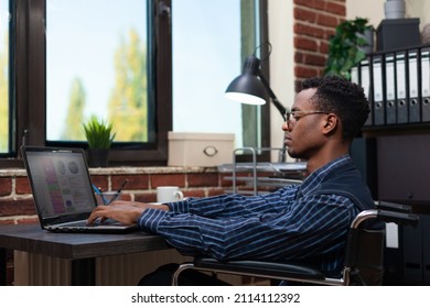 Startup marketing specialist living with disability working on sales statiscs pie charts using laptop at desk. African american business employee with glasses analyzing marketing data. - Powered by Shutterstock