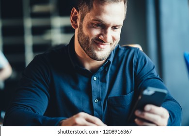 Startup And Millenial Business Concept. Portrait Of Manager In Office Smiling And Using Mobile Phone