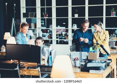 Startup And Millenial Business Concept. Team Of Four People Works Together In Big Open Space Office