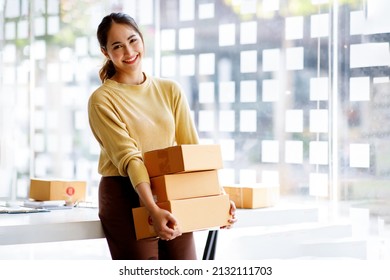 Startup small business entrepreneur of freelance Asian woman using a laptop with box Cheerful success Asian woman her hand lifts up online marketing packaging box and delivery SME idea concept